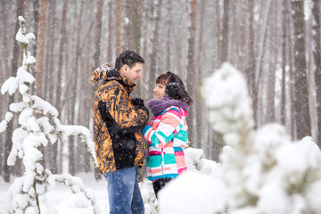 Winter snowfall, young couple looking at each other and smiling in snowy winter day