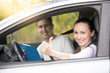 © fizkes - Lifestyle portrait of young happy confident lady have just finished drivers education class, showing thumb up, experienced casual instructor, holding a file folder is smiling too
