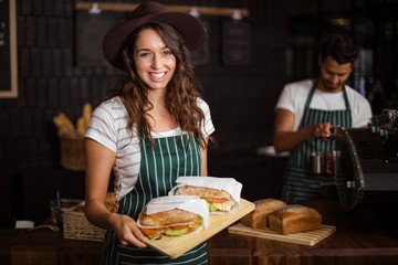 Wall Mural - Smiling barista holding sandwiches