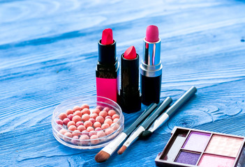 cosmetic palette and lipstick on wooden background