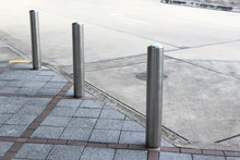 Stainless Steel Bollards On Grey Stone Pavement Of Car Park