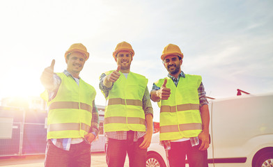 happy male builders in high visible vests outdoors