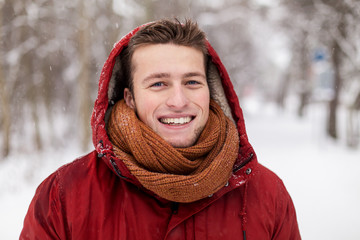 Wall Mural - happy man in winter jacket with hood outdoors