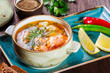 Fish soup with salmon and shrimps, dill, potatoes, lemon, peppers and bread on dark wooden background, healthy food. Top view