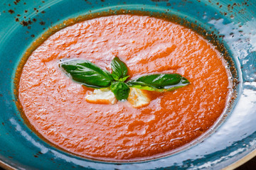 Tomato gazpacho soup with basil, feta cheese, ice and bread on dark wooden background, Spanish cuisine. Ingredients on table. Top view