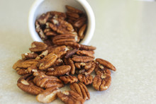 Pecans Spilling Out Of A Container, Positioned Close Left