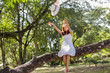 © chaunpis - Young teen girl sitting on tree and holding balloons in hand