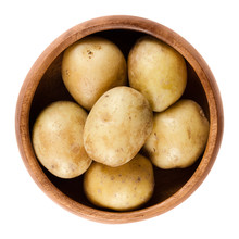 Raw Mini Potatoes In Wooden Bowl. Edible Tuber Of Nightshade Solanum Tuberosum, A Starchy Crop. Isolated Macro Food Photo Close Up From Above On White Background.