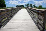 Fototapeta Pomosty - Wooden Walking Path with Blue Sky and White Clouds