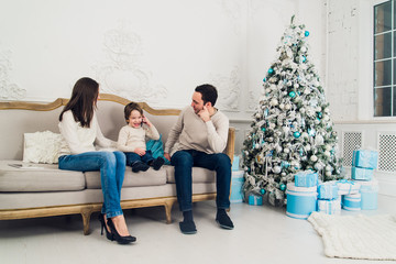 family phone talking - cute little boy, his mother and father are sitting on the sofa