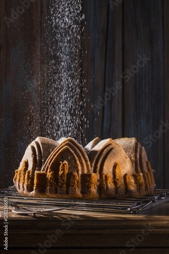 Fotografie, Obraz Sprinkling Powdered Sugar over Apple Spice Cake