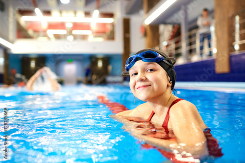 Plakat Dziewczyny dziecka pływaczka w czerwonym kostiumu kąpielowym na tle