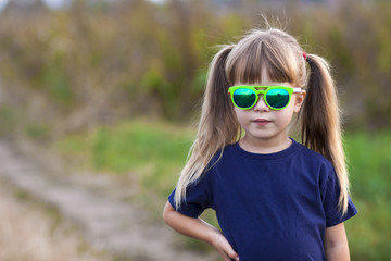 Poster - Portrait of little fashionable girl in green sunglasses outdoors