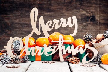 Wall Mural - Christmas home decoration, Wood rustic Xmas background with wooden letters.Dry Oranges,cinnamon sticks,Nuts.Ornaments.Gifts in Boxes