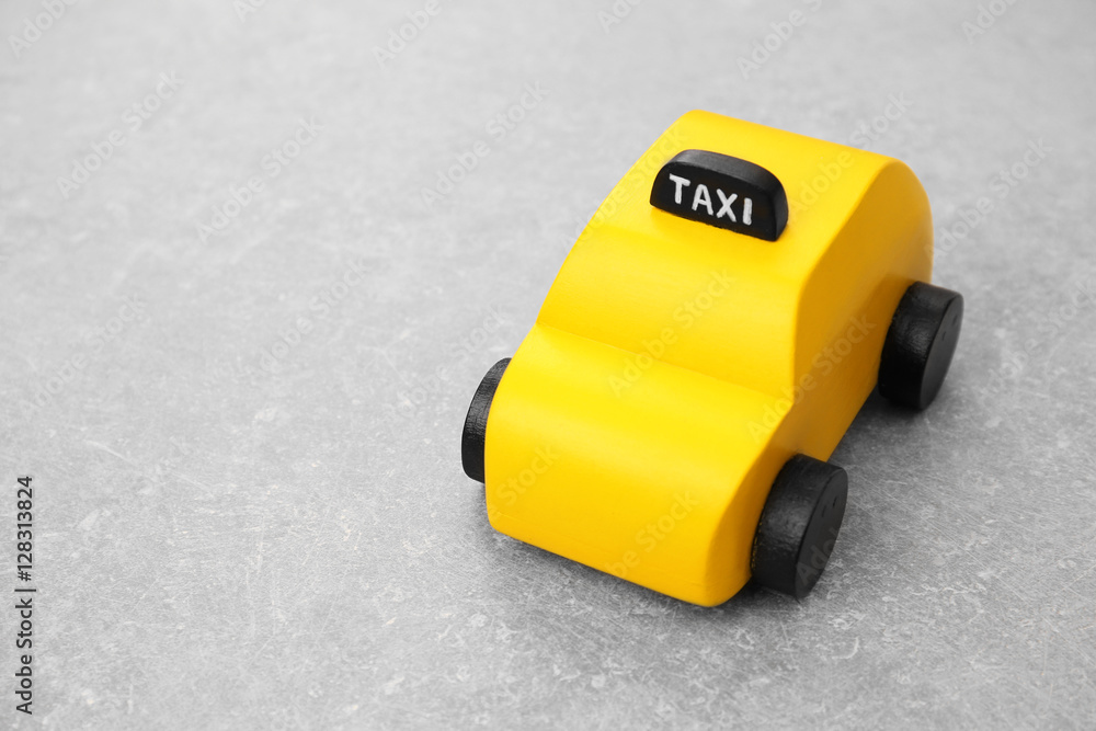 Yellow toy taxi cab on grey background