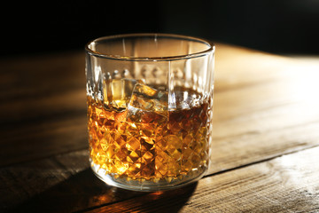 Glass of whisky on wooden table closeup