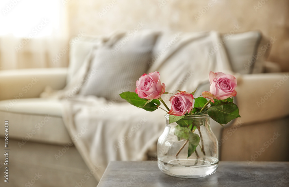 Fresh roses in glass vase on table in the room