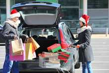 Young Couple Loading Christmas Purchases Into Car Trunk On Shopping Mall Parking