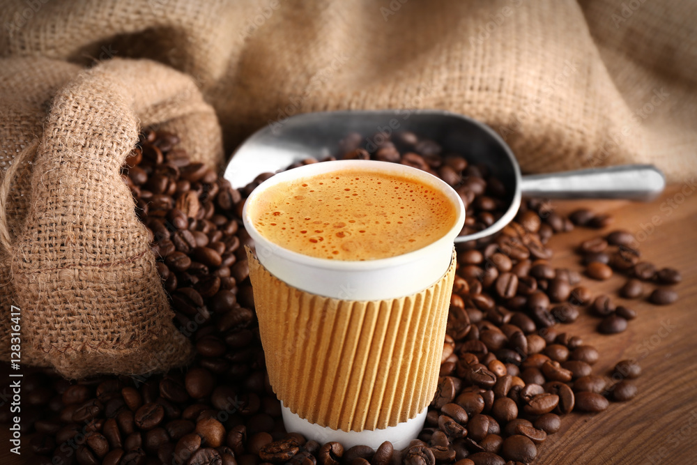 Cup of coffee with roasted beans on wooden table closeup