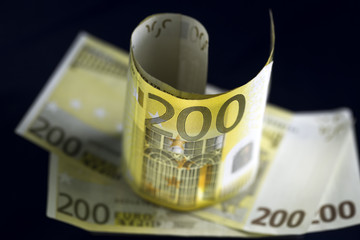 Several Two hundred euro banknotes on dark background. Two banknotes is standing on anothers. Selective focus.