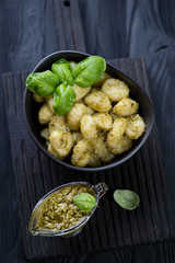 Poster - Potato gnocchi with basil pesto over black wooden background