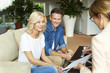 © sepy - Investment advisor and her clients. Shot of a happy middle aged couple consulting with real estate agent businesswoman in their home while sitting on couch.