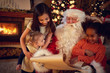 Santa Claus father reading wish list with mixed race little girl