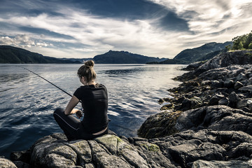 Young woman is fishing in Norway