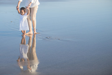 Wall Mural - mother is teaching her daughter walks on the beach