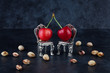 Two red delicious ripe cherries on vintage small silver chairs  with cherrystones on dark background with copy space. Relationship concept