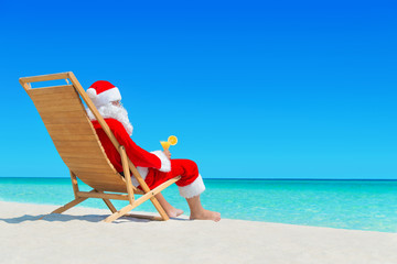 Canvas Print - Christmas Santa Claus with fresh juice on sunlounger at tropical ocean beach