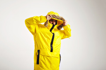 Wall Mural - Young snowboarder putting on hood of his bright yellow snowboarding coat isolated on white