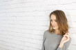 © Studio-FI - Woman standing next to a white brick wall smiling and happy