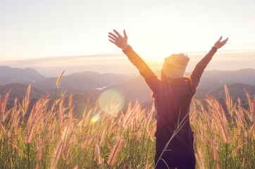 carefree happy woman enjoying nature on grass meadow on top of mountain cliff with sunrise. beauty g