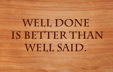 Well done is better than well said - motivational quote on wooden red oak background