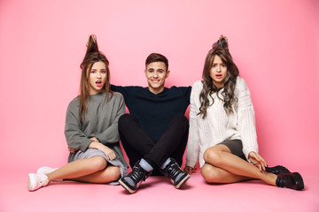 Wall Mural - Young handsome guy smiling holding girls' hair over pink background.