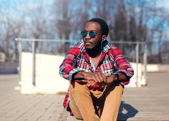 Wall Mural - Fashion portrait african man with earphones listens to music in city