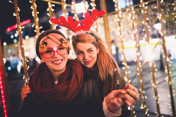 Beautiful young women enjoying Christmas or New Year night on a city street. 