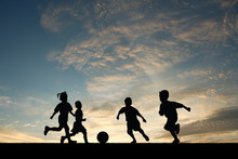 Children Playing Soccer At Sunset.