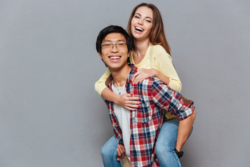 Wall Mural - Portrait of a young multiracial couple enjoying piggyback ride