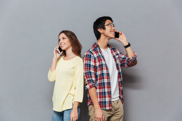 Poster - Portrait of a young multiracial couple talking on mobile phones