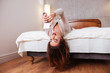 Woman lying upside down in bed and talking on phone