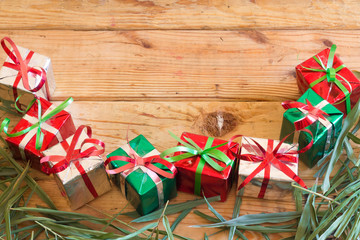 Christmas gift box with green leaves on wood background for Chri