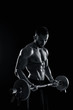 © nazarovsergey - muscular man lifting weights over dark background