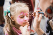 © sushytska - woman painting face of kid outdoors