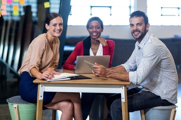 Wall Mural - Colleagues sitting at their desk smiling at camera