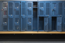 Blue Metal Cage Lockers In A Locker Room With Some Doors Open And Some Closed With A Wooden Bench