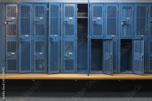 Fotografia, Obraz Blue metal cage lockers in a locker room with some doors open and some closed wi