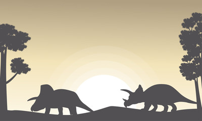 Silhouette of two triceratops on the hill scenery