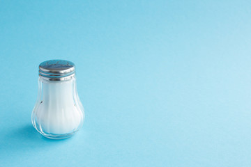 Salt shaker with salt on blue background